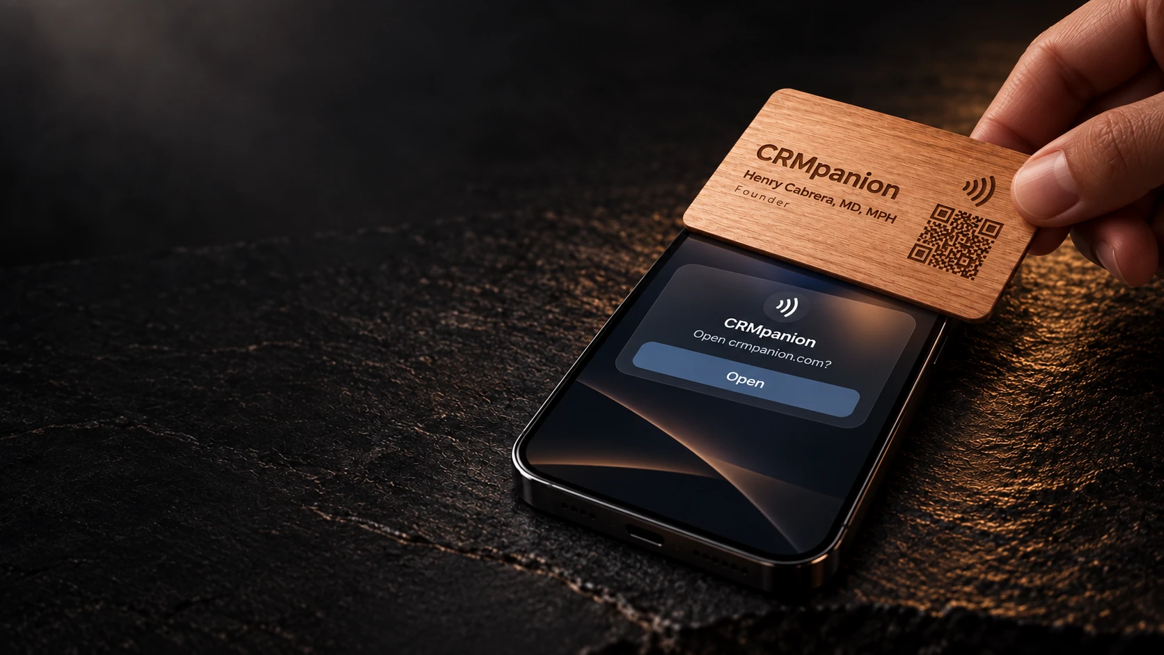 A hand tapping Henry Cabrera's wooden CRMpanion card on a phone showing an NFC link notification